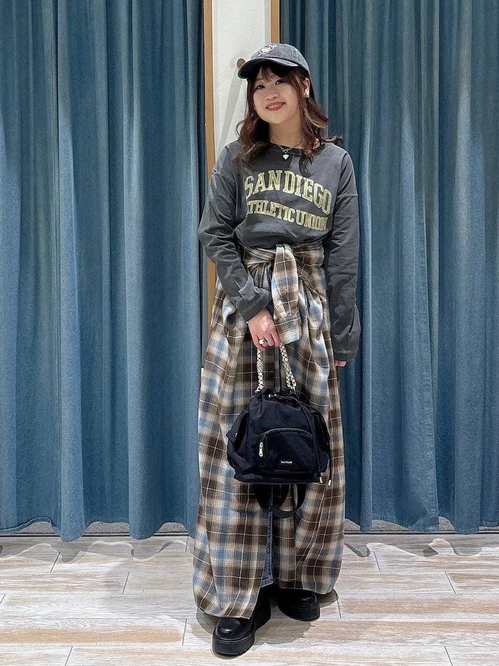 ブラック系のブーツ、ブラック系のハンドバッグ、グレー系のTシャツ/カットソーを着用したレディースの冬コーディネートの4枚目の写真