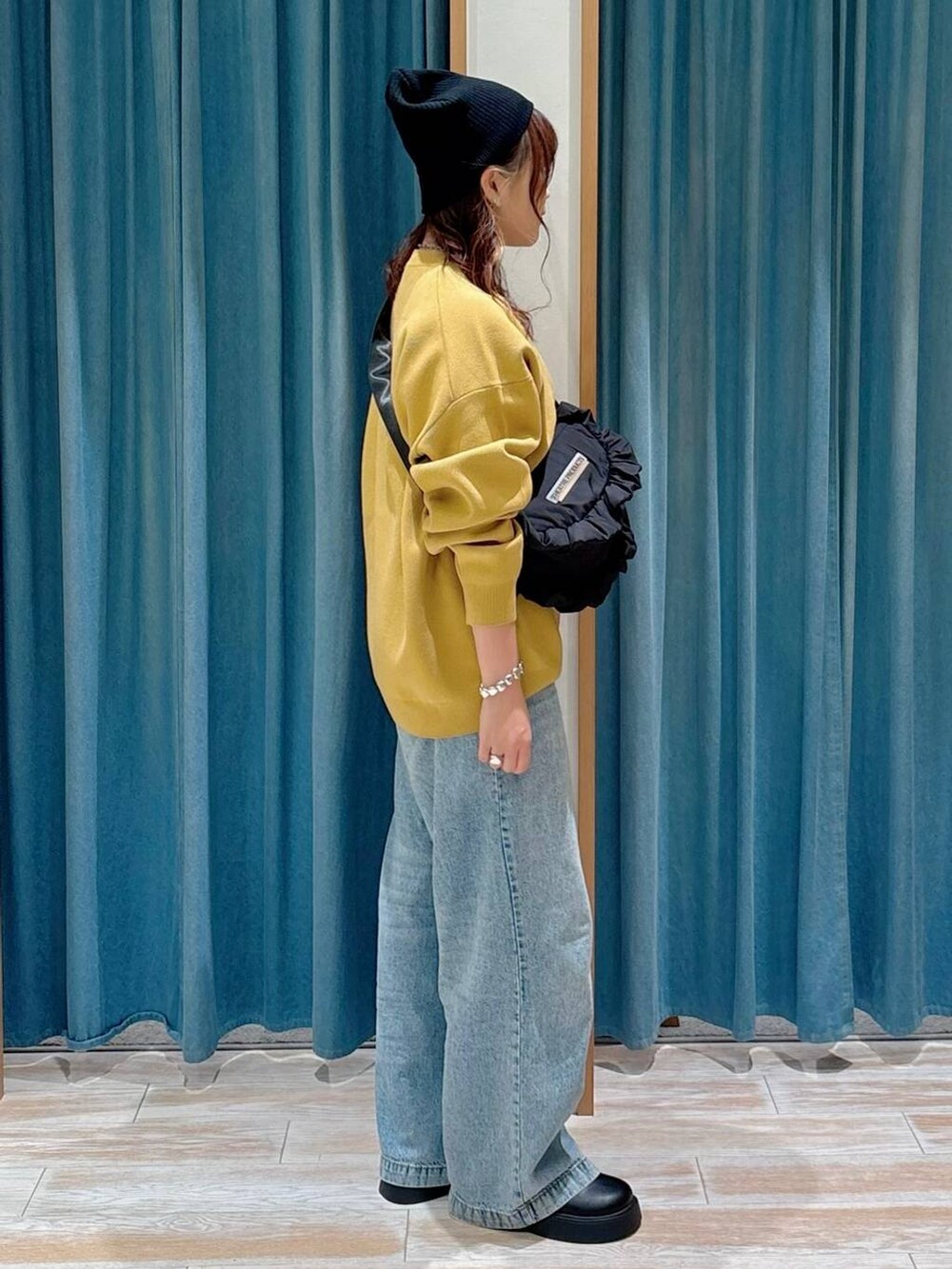 ブルー系のデニムパンツ、ブラック系のサンダル、ブラック系のショルダーバッグを着用したレディースの夏コーディネートの2枚目の写真