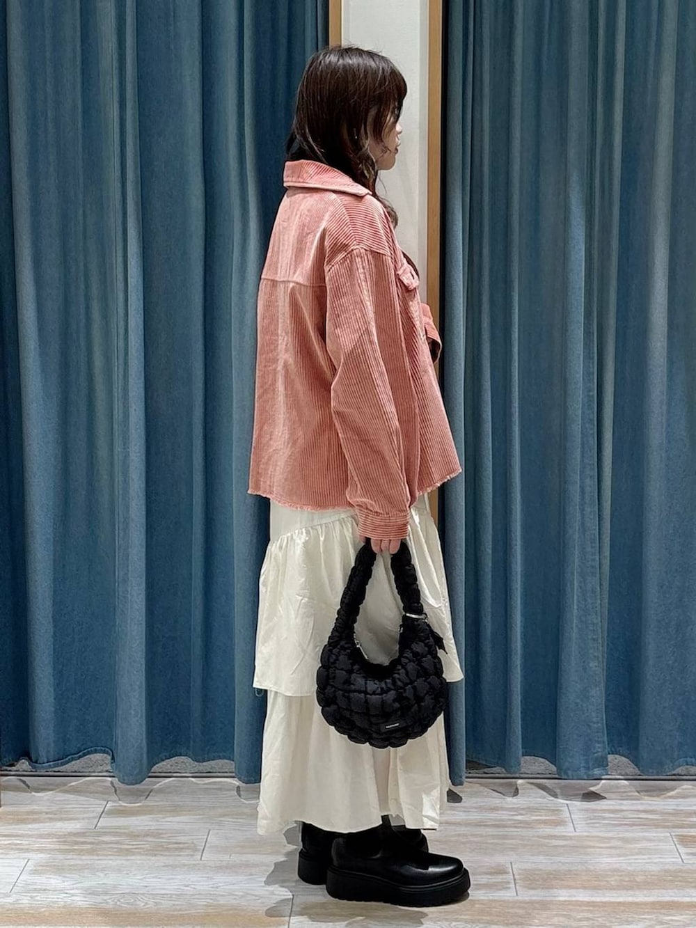 ブラック系のハンドバッグ、ブラック系のブーツ、ベージュ系のスカートを着用したレディースの秋コーディネートの2枚目の写真