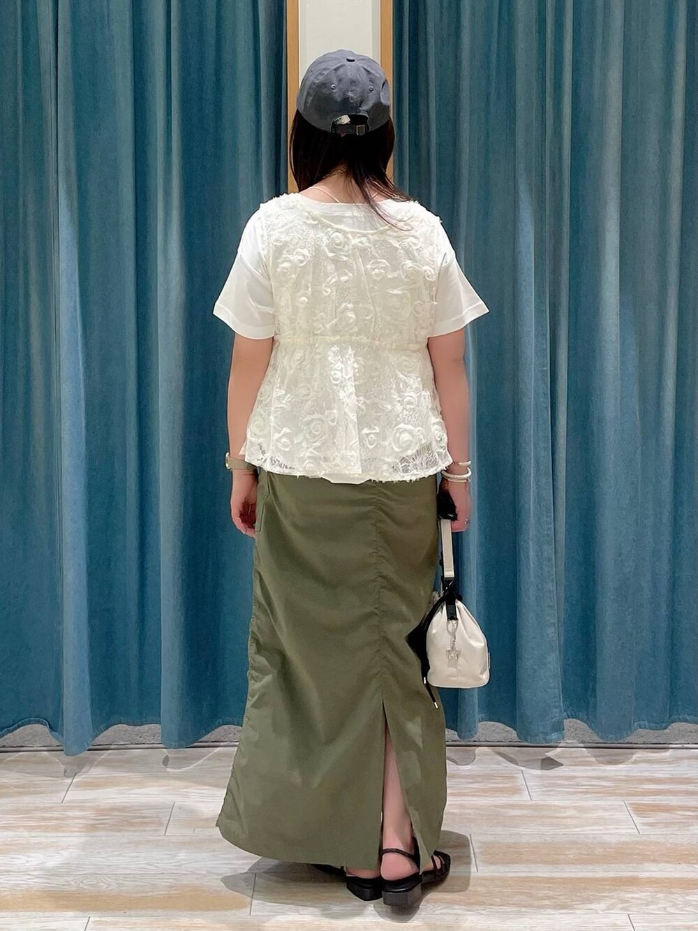 ホワイト系のTシャツ/カットソー、グリーン系のスカート、ブラック系のサンダルを着用したレディースの夏コーディネートの3枚目の写真