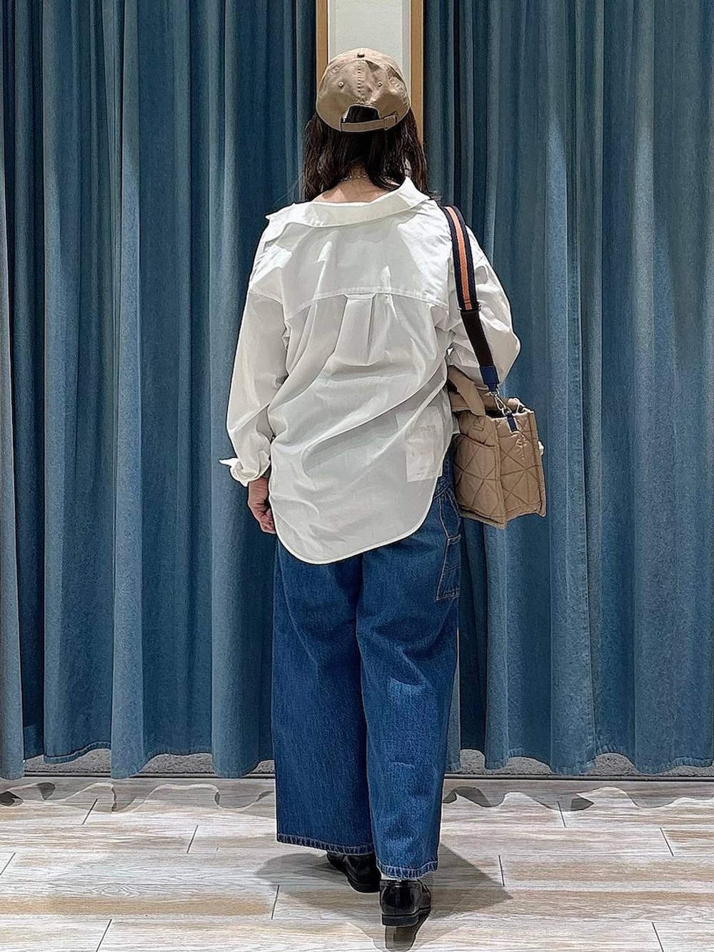 ベージュ系のショルダーバッグ、ブルー系のデニムパンツ、ブラック系のローファーを着用したレディースの春コーディネートの3枚目の写真