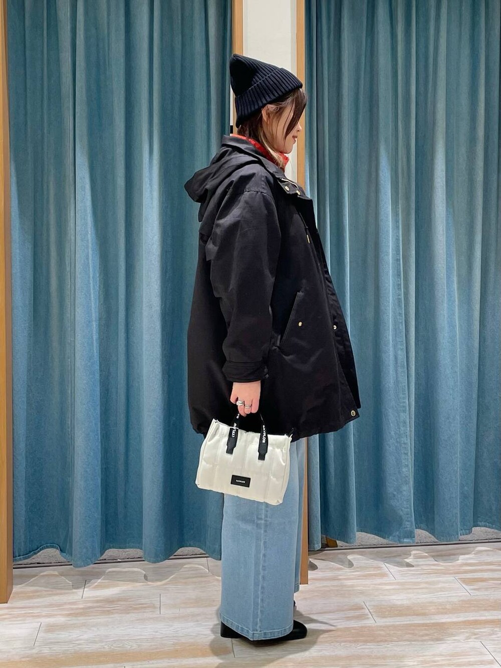 ブラック系のブーツ、オレンジ系のニット/セーター、ブラック系のマウンテンパーカーを着用したレディースの冬コーディネートの2枚目の写真