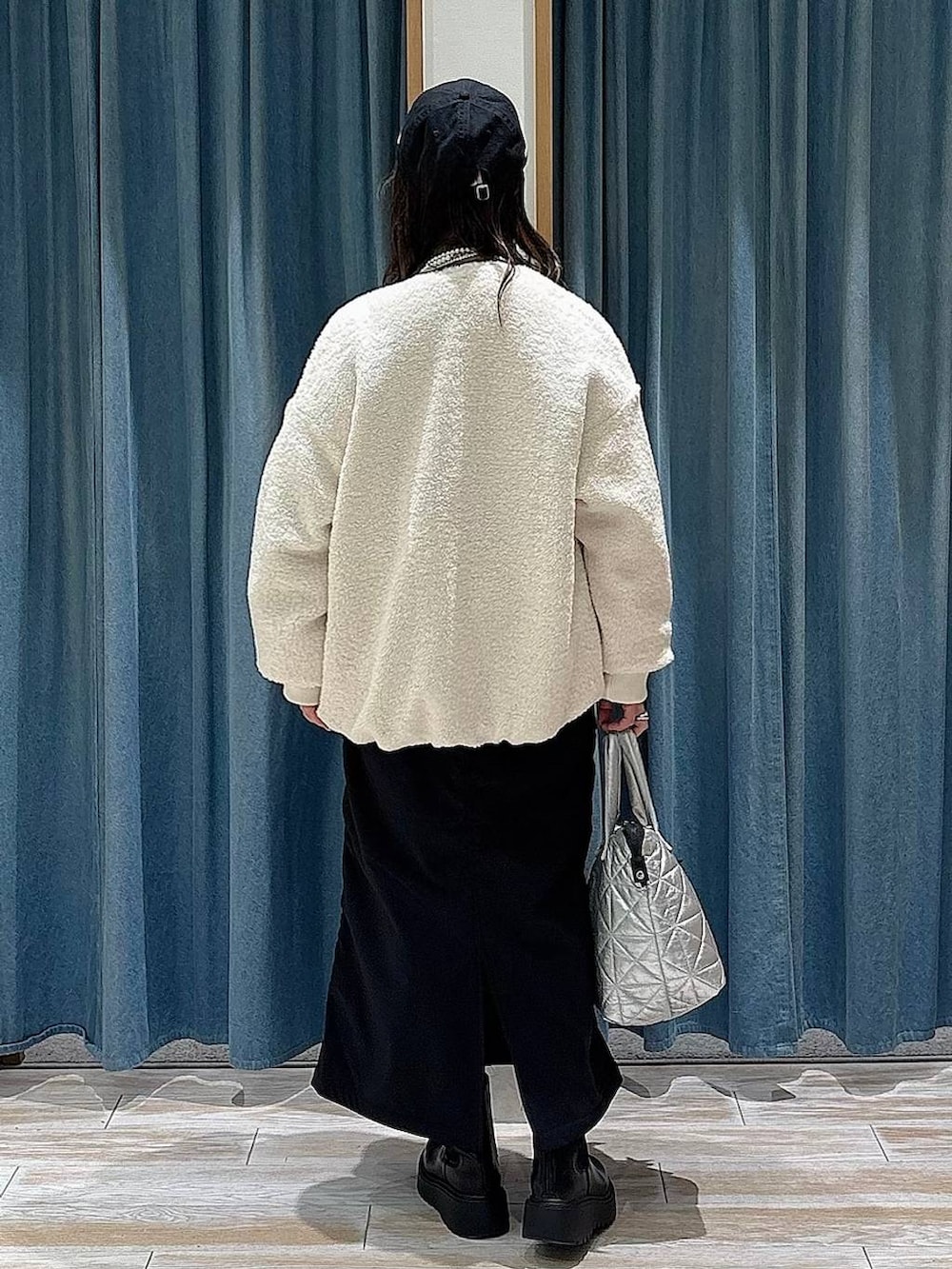 ブラック系のスカート、ブラック系のブーツ、イエロー系のニット/セーターを着用したレディースの冬コーディネートの3枚目の写真