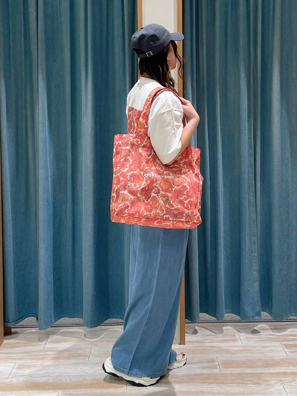 ブルー系のその他パンツ、ホワイト系のTシャツ/カットソー、レッド系のトートバッグを着用したレディースの春コーディネートの3枚目の写真