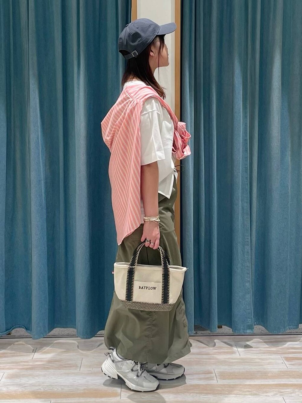 ベージュ系のトートバッグ、ホワイト系のスニーカー、グリーン系のスカートを着用したレディースの春コーディネートの2枚目の写真