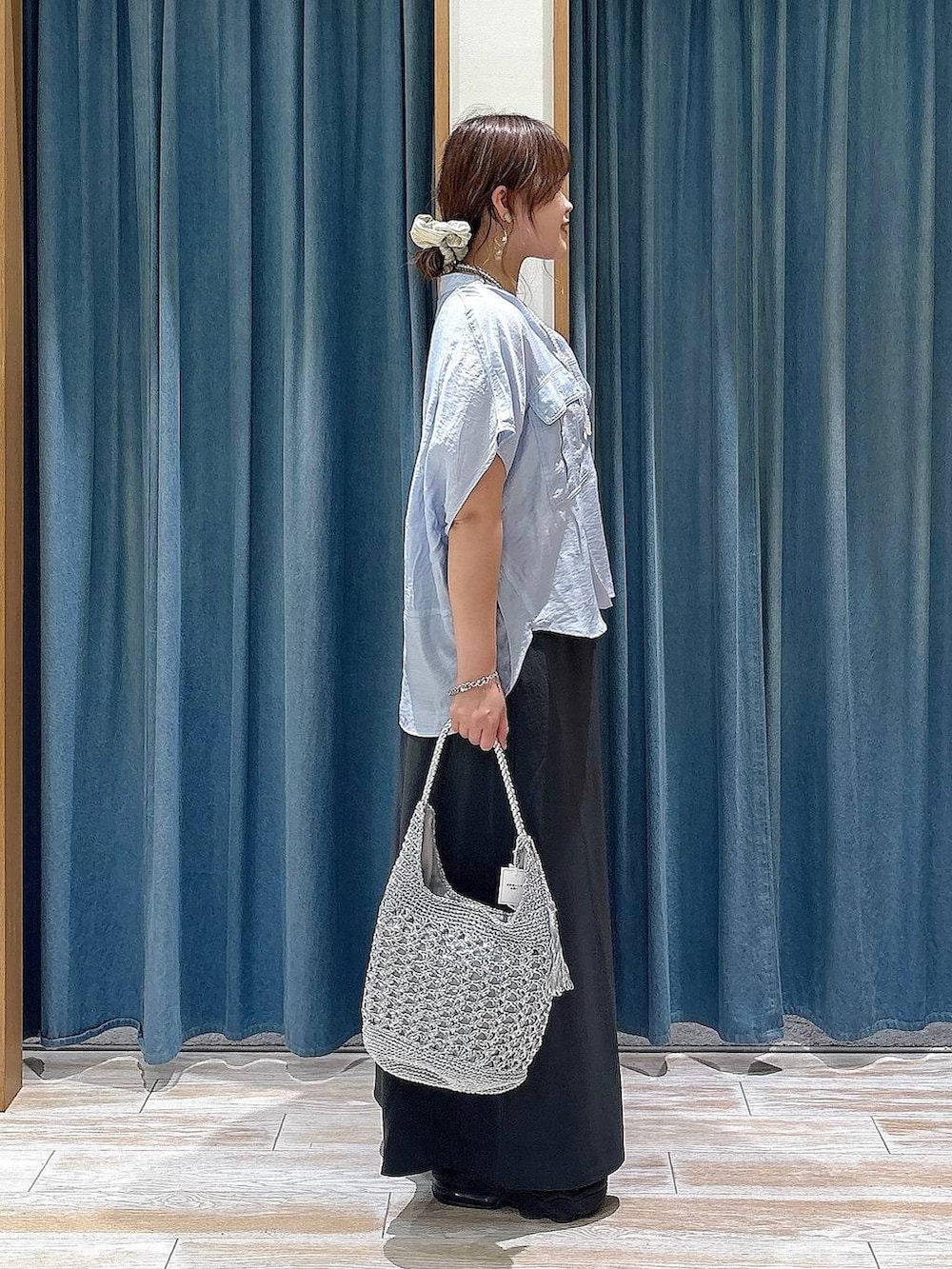 ブルー系のシャツ/ブラウス、グレー系のスカート、シルバー系のショルダーバッグを着用したレディースの夏コーディネートの2枚目の写真