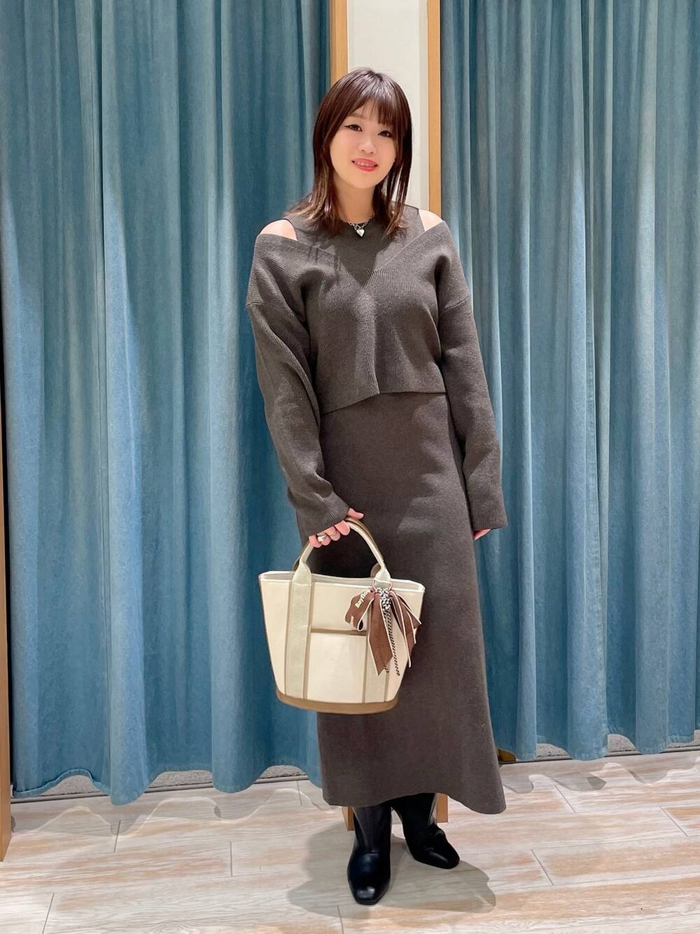 ホワイト系のダウンジャケット/コート、ブラック系のブーツ、ホワイト系のトートバッグを着用したレディースの冬コーディネートの3枚目の写真