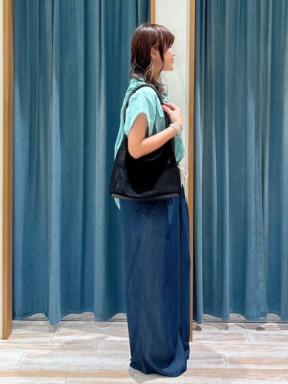 グリーン系のシャツ/ブラウス、シルバー系のサンダル、ブラック系のハンドバッグを着用したレディースの夏コーディネートの2枚目の写真