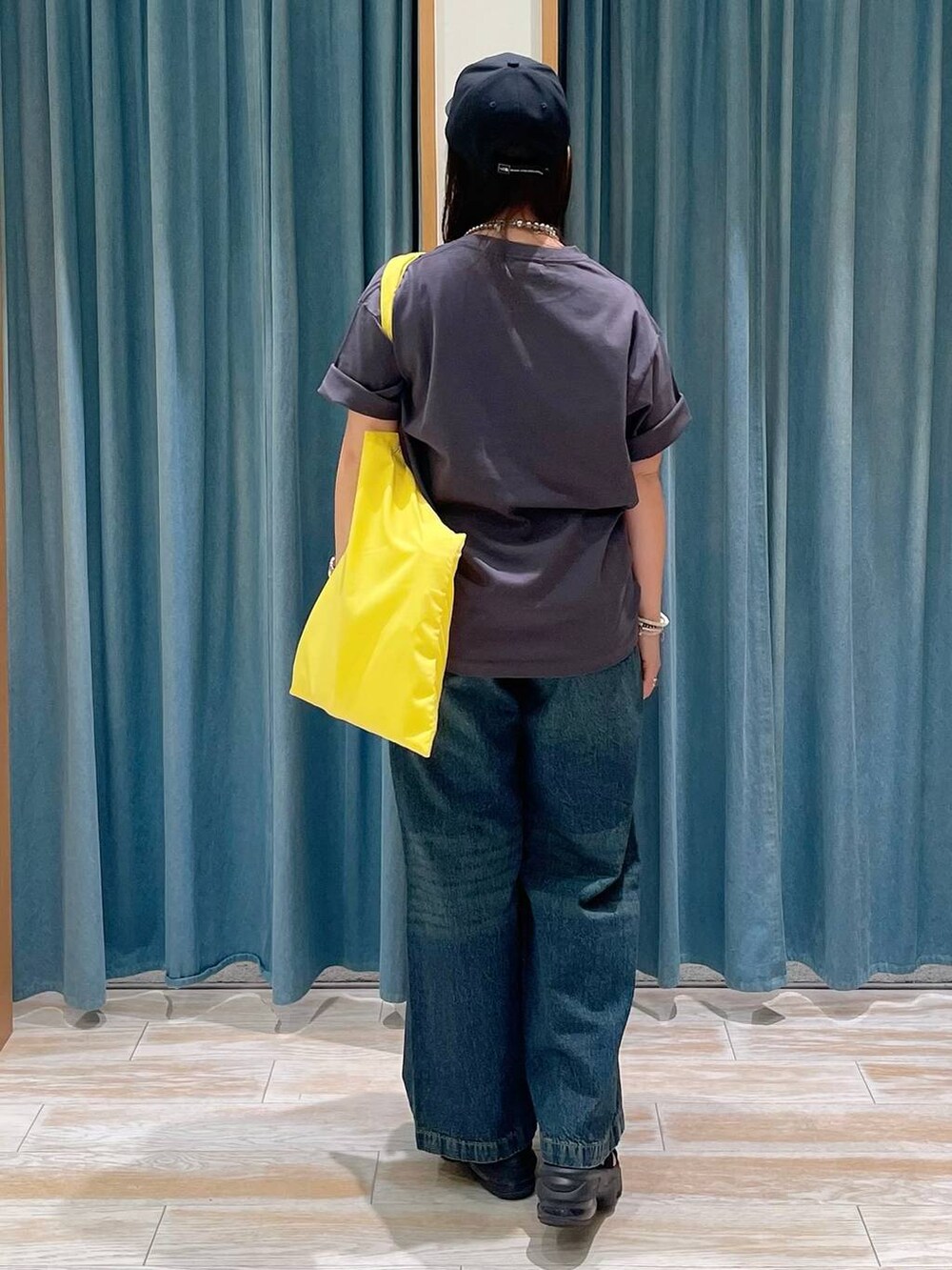 ブルー系のデニムパンツ、イエロー系のトートバッグ、グレー系のTシャツ/カットソーを着用したレディースの夏コーディネートの3枚目の写真