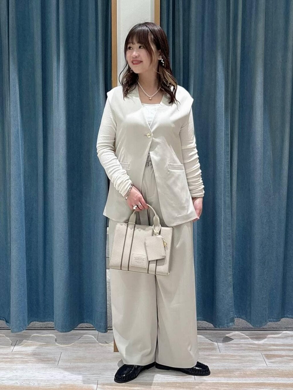 ベージュ系のベスト、ベージュ系のスラックス、ベージュ系のハンドバッグを着用したレディースの冬コーディネートの2枚目の写真