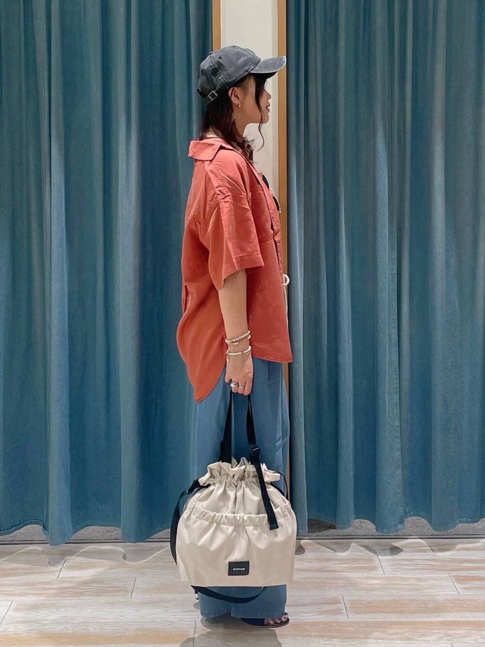 ホワイト系のキャミソール、ホワイト系のトートバッグ、オレンジ系のシャツ/ブラウスを着用したレディースの春コーディネートの2枚目の写真