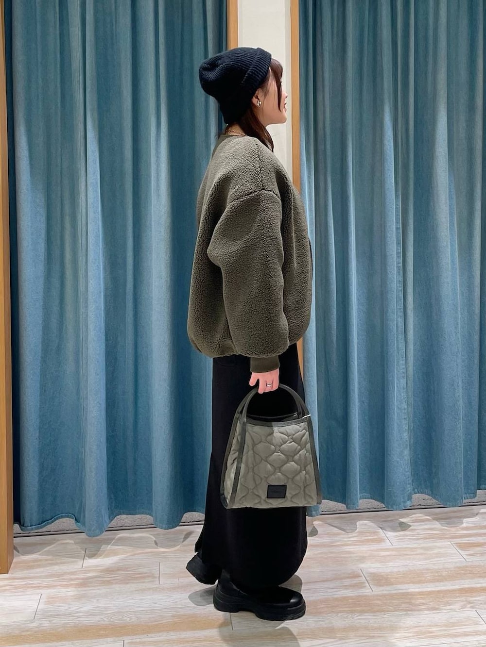 グリーン系のハンドバッグ、ブラック系のブーツ、ホワイト系のTシャツ/カットソーを着用したレディースの冬コーディネートの2枚目の写真