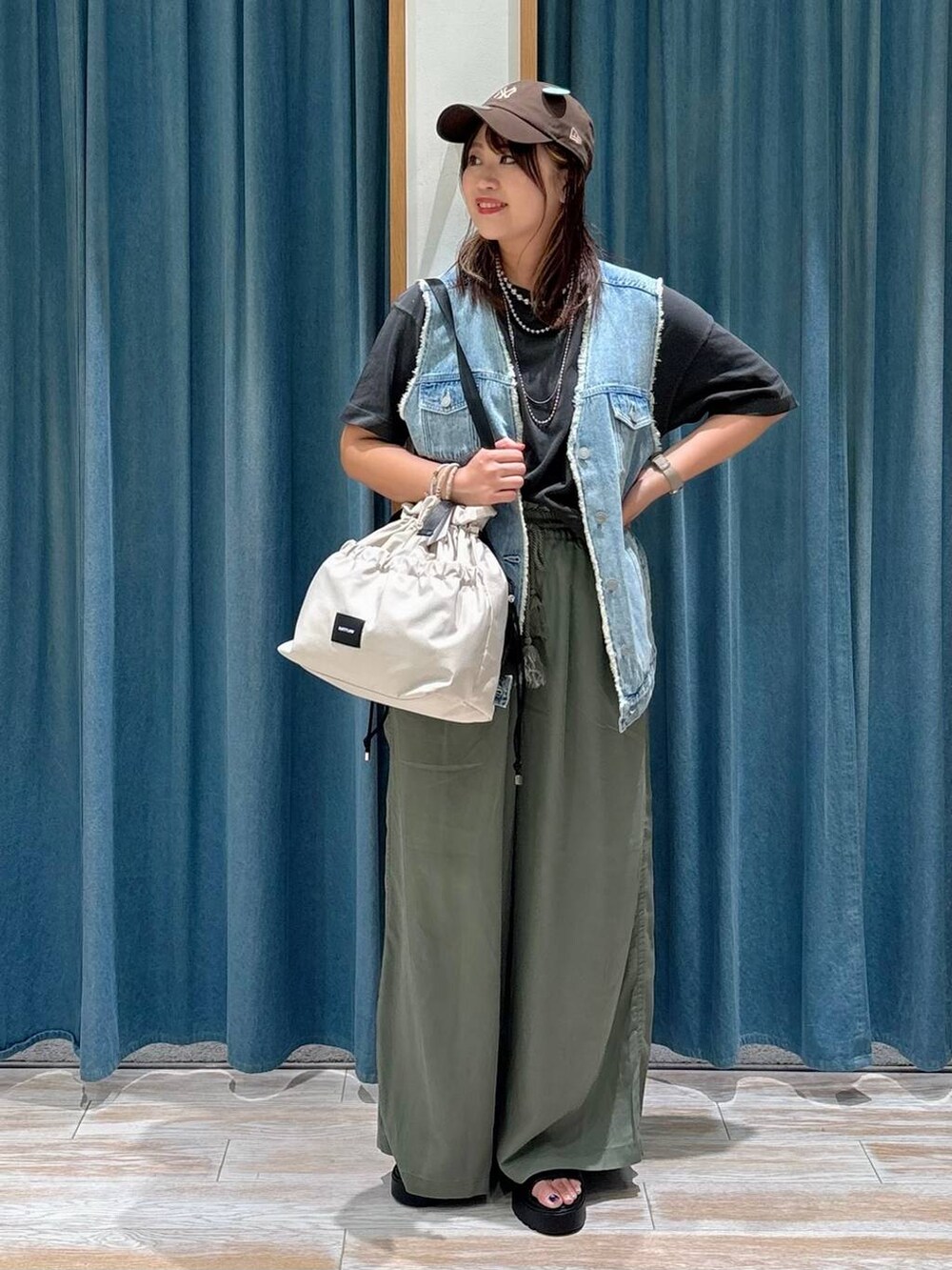 ホワイト系のトートバッグ、グリーン系のその他パンツ、ブルー系のベストを着用したレディースの夏コーディネートの4枚目の写真