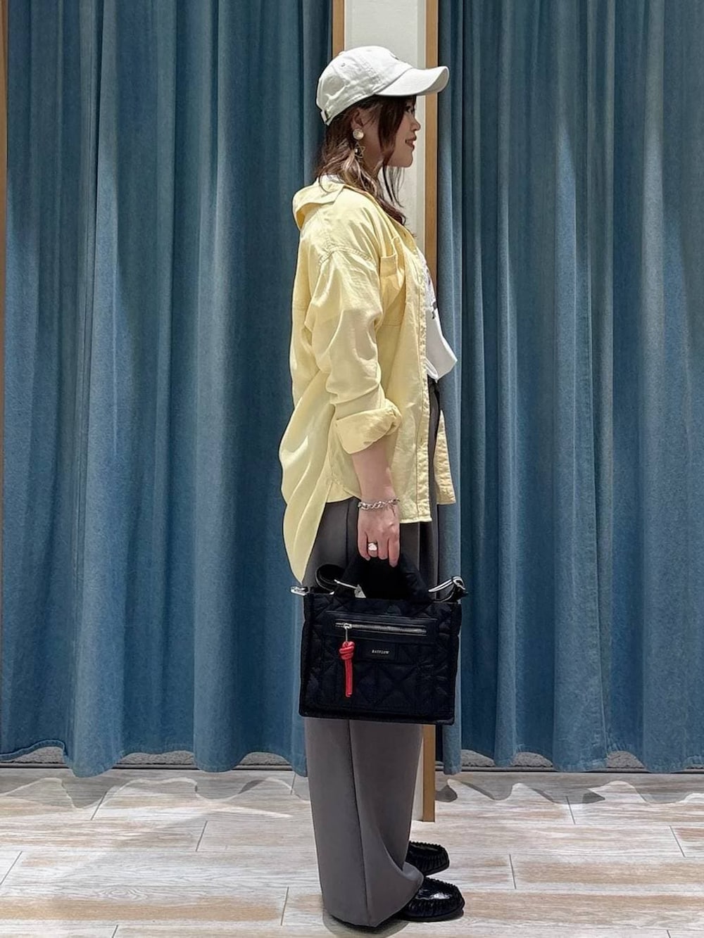 ブラック系のショルダーバッグ、イエロー系のシャツ/ブラウス、ホワイト系のTシャツ/カットソーを着用したレディースの春コーディネートの2枚目の写真