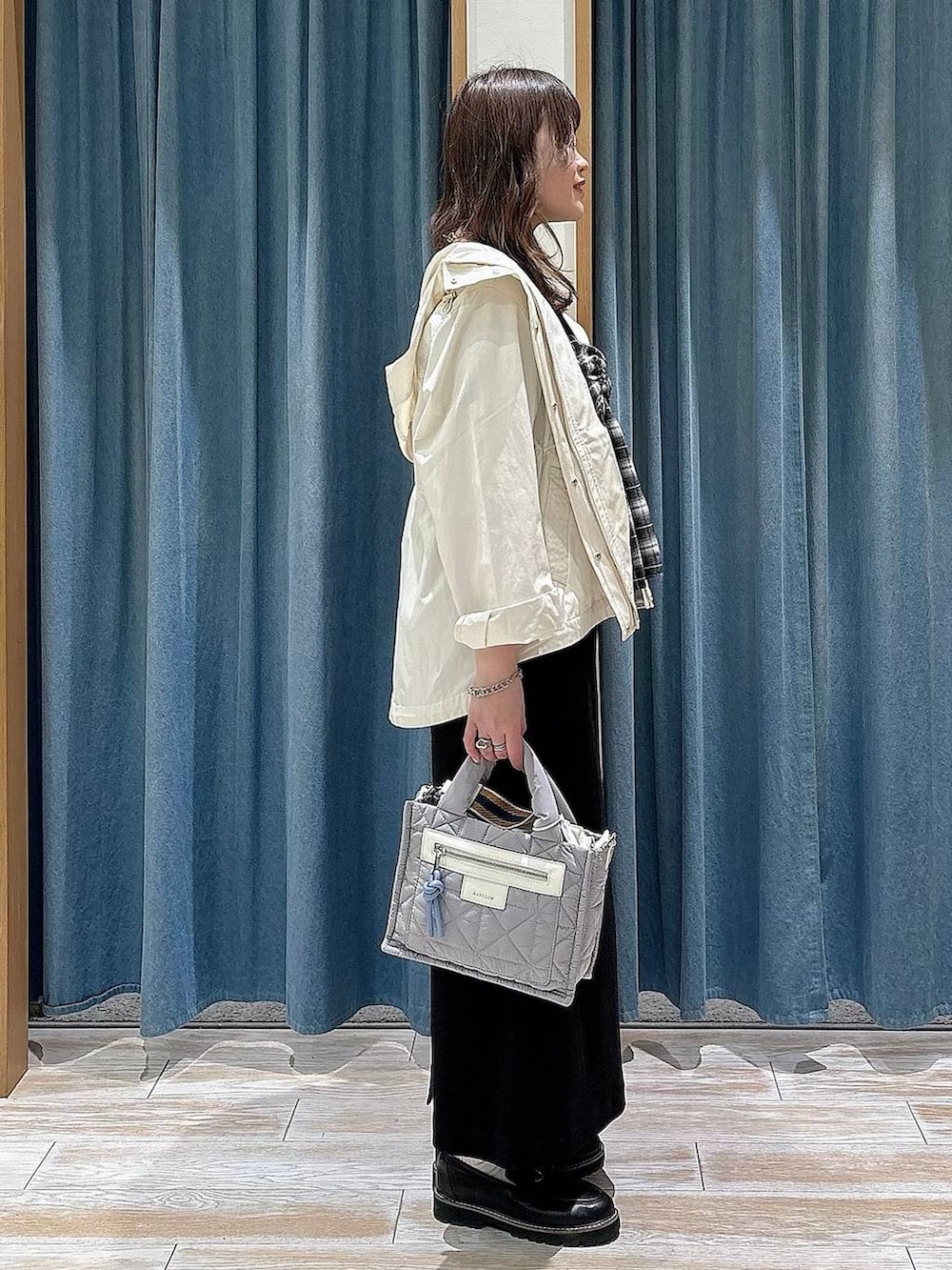 グレー系のショルダーバッグ、ホワイト系のマウンテンパーカー、ブラック系のローファーを着用したレディースの春コーディネートの2枚目の写真