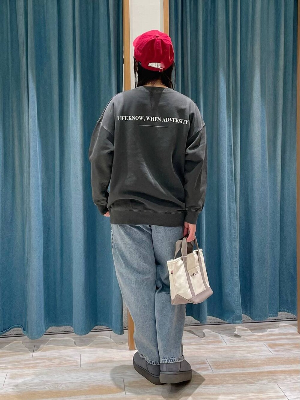 ホワイト系のスウェット、グレー系のトートバッグ、グレー系のブーツを着用したレディースの冬コーディネートの3枚目の写真