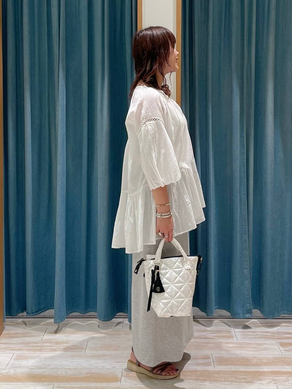 ホワイト系のハンドバッグ、ホワイト系のシャツ/ブラウス、グレー系のスカートを着用したレディースの春コーディネートの2枚目の写真