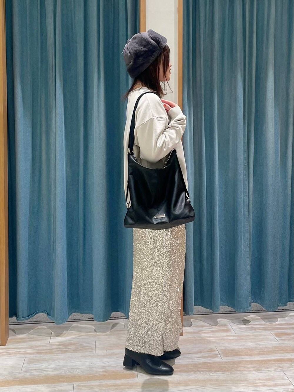 ブラック系のブーツ、ブラック系のショルダーバッグ、ベージュ系のスカートを着用したレディースの冬コーディネートの2枚目の写真