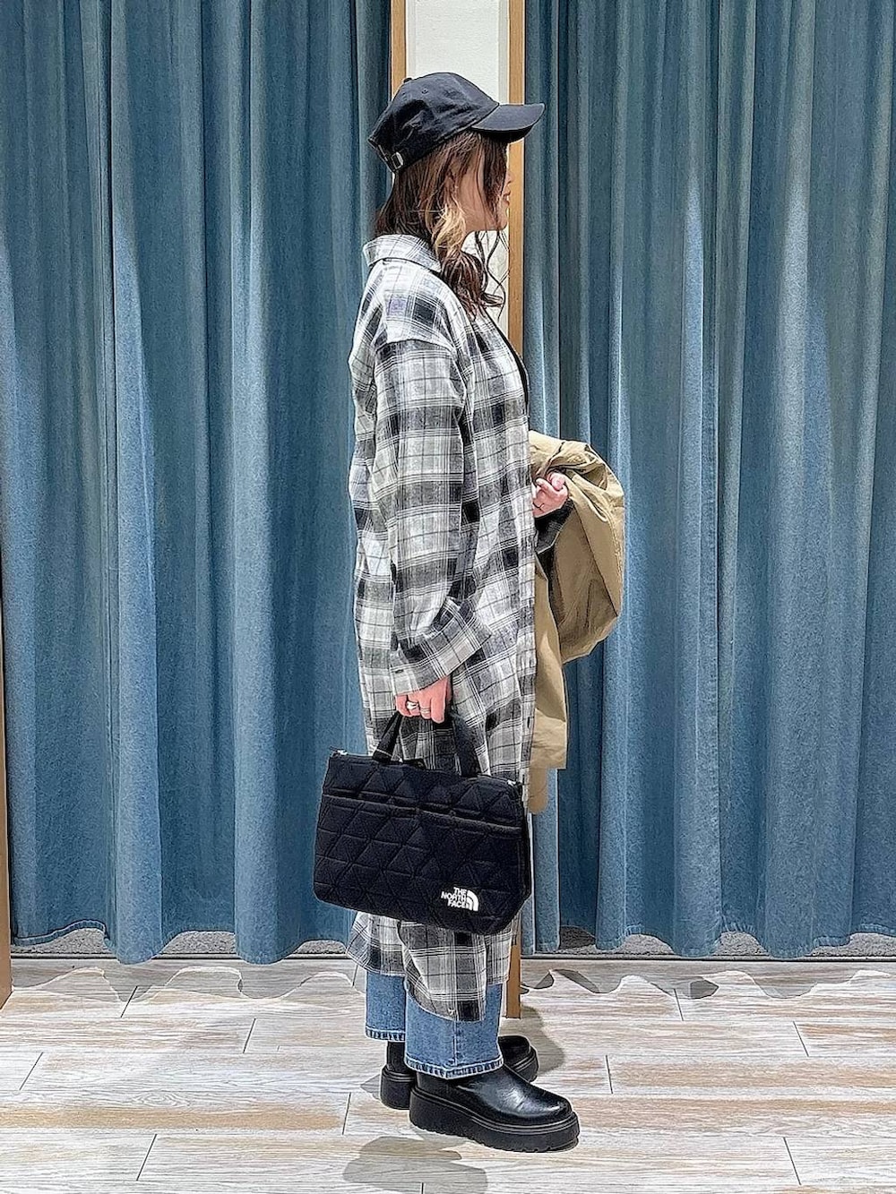 ブラック系のブーツ、ブラック系のトートバッグ、ブルー系のデニムパンツを着用したレディースの冬コーディネートの2枚目の写真