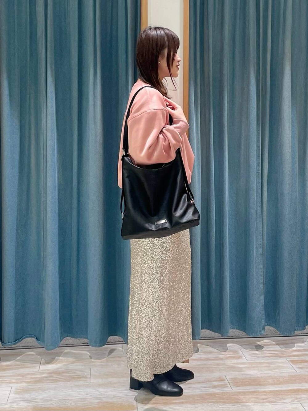 ブラック系のブーツ、ブラック系のショルダーバッグ、ベージュ系のスカートを着用したレディースの冬コーディネートの2枚目の写真