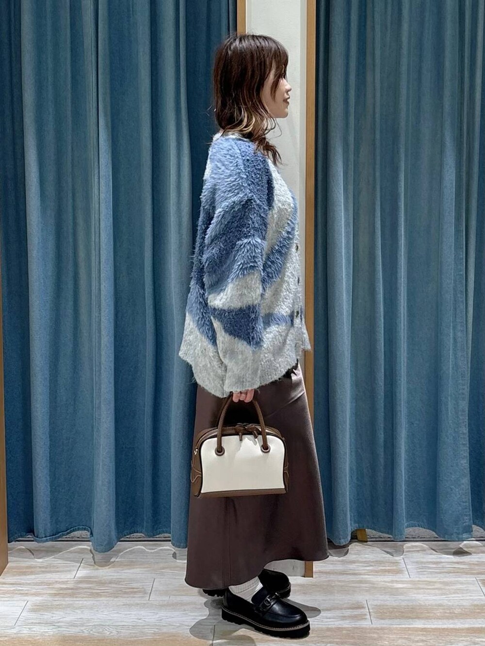 ホワイト系のハンドバッグ、ブラック系のローファー、ブルー系のカーディガン/ボレロを着用したレディースの秋コーディネートの2枚目の写真