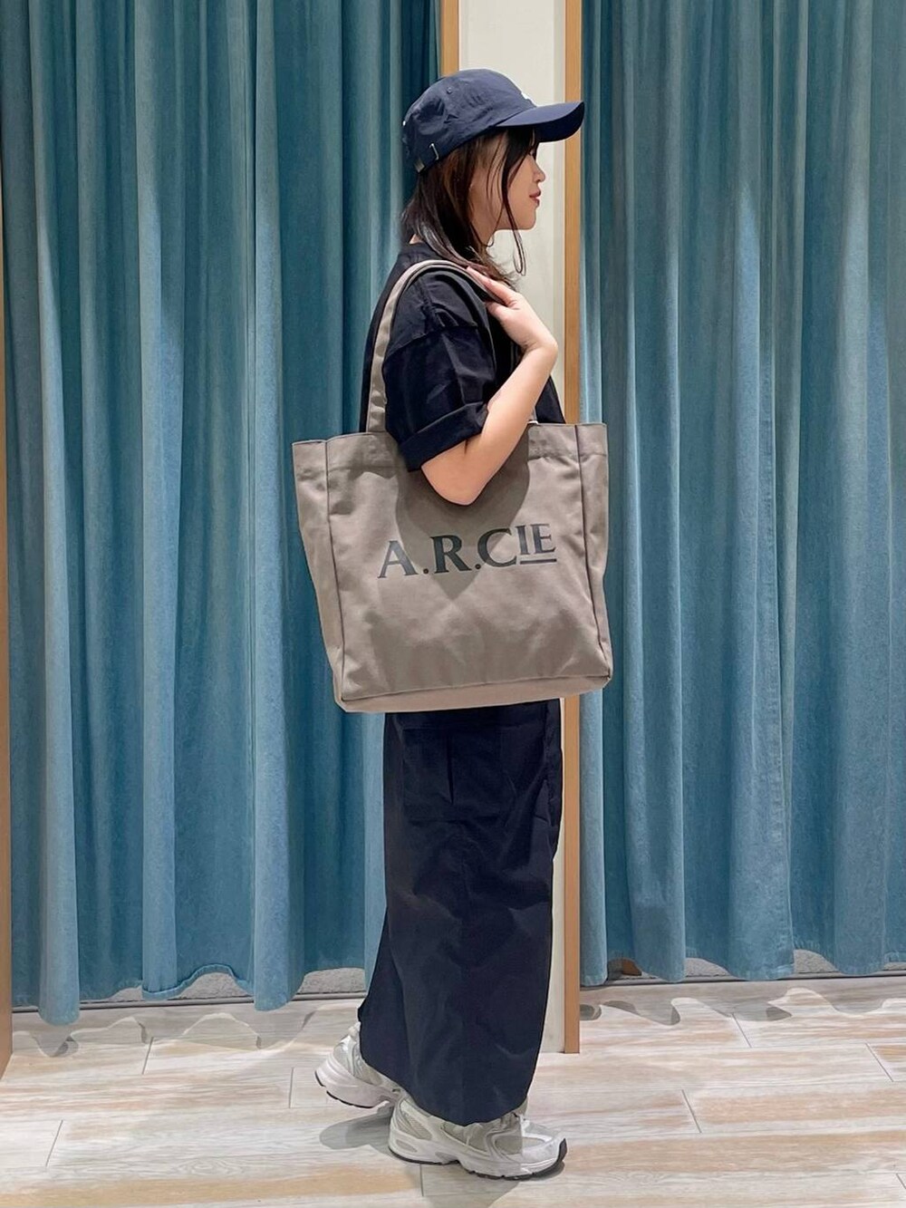 ブラック系のスカート、グリーン系のトートバッグ、ブラック系のTシャツ/カットソーを着用したレディースの春コーディネートの3枚目の写真