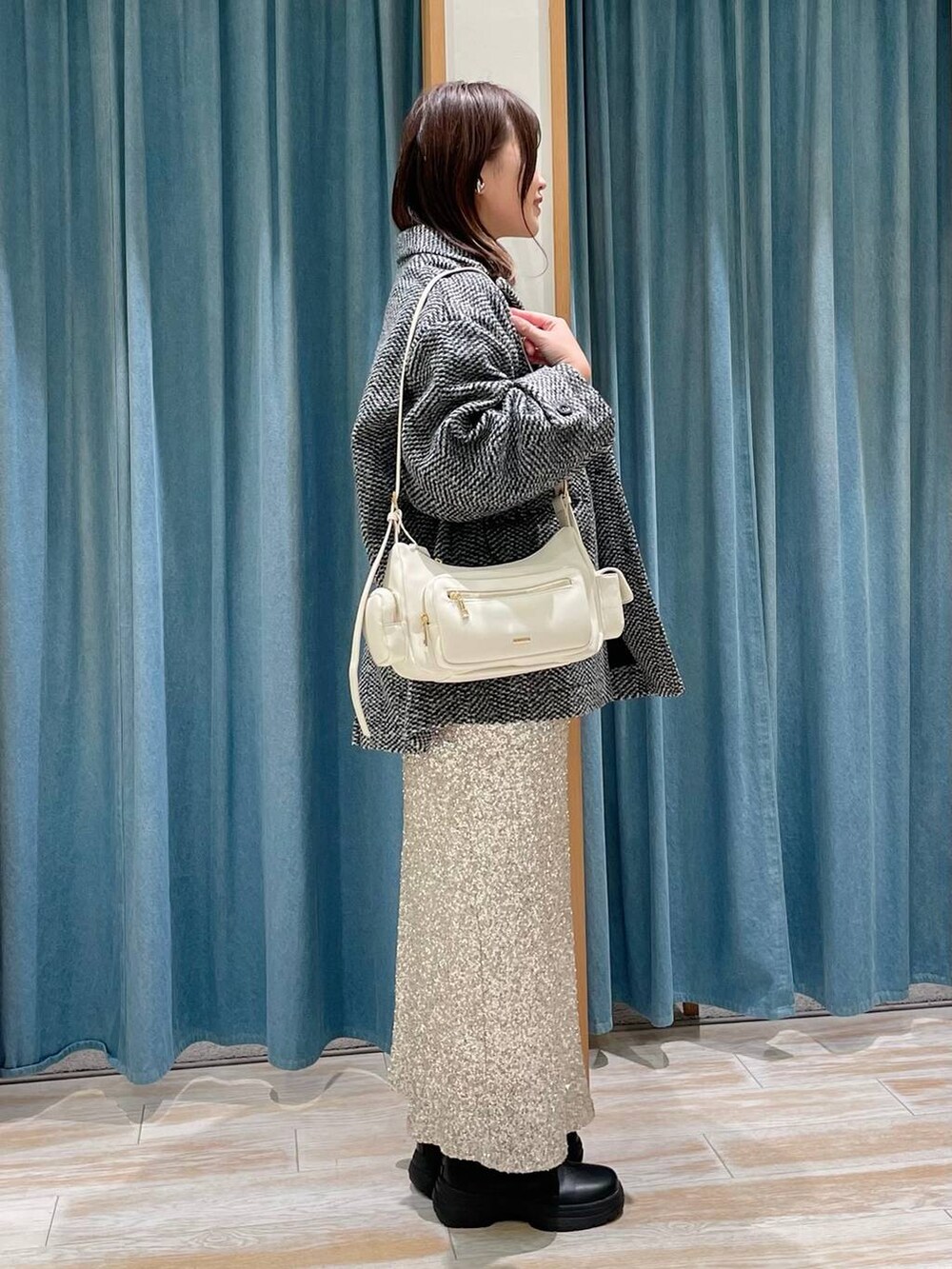 ホワイト系のハンドバッグ、ブラック系のブーツ、グレー系のその他アウターを着用したレディースの冬コーディネートの2枚目の写真