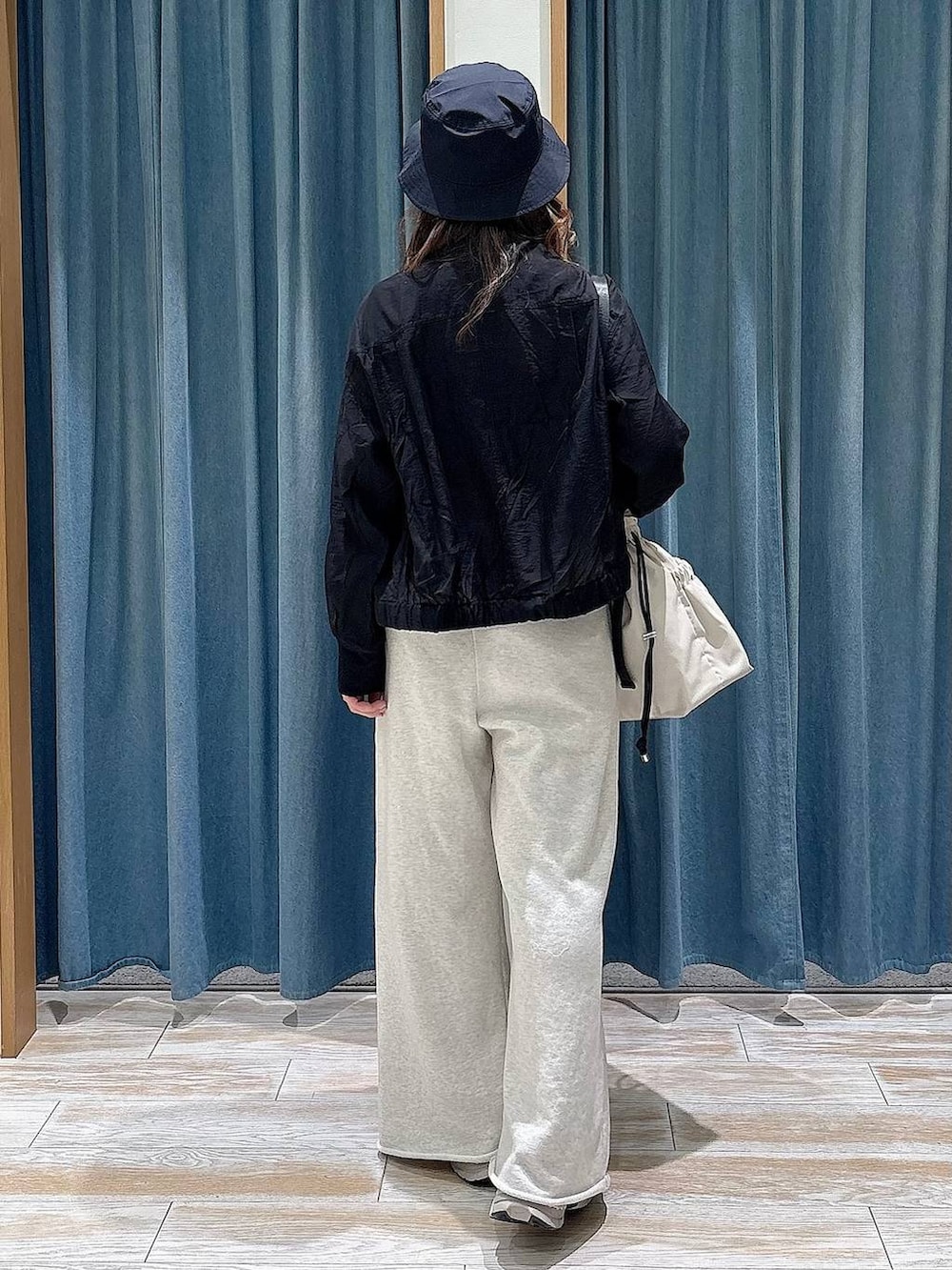 ホワイト系のトートバッグ、ブラック系のブルゾン、ホワイト系のスウェットパンツを着用したレディースの春コーディネートの3枚目の写真