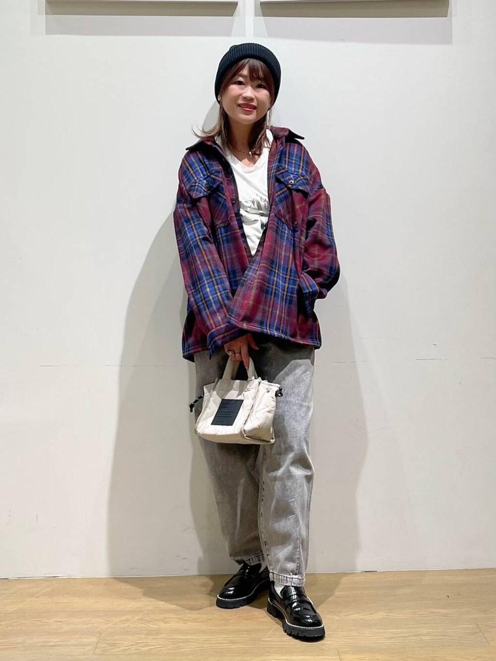 ホワイト系のショルダーバッグ、ブラック系のデニムパンツ、ブラック系のローファーを着用したレディースの秋コーディネートの2枚目の写真