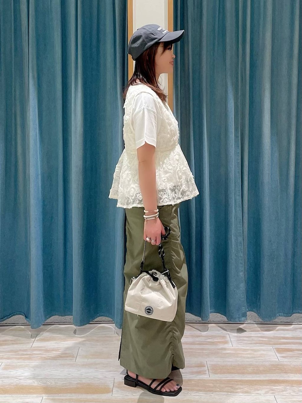 ホワイト系のTシャツ/カットソー、グリーン系のスカート、ブラック系のサンダルを着用したレディースの夏コーディネートの2枚目の写真