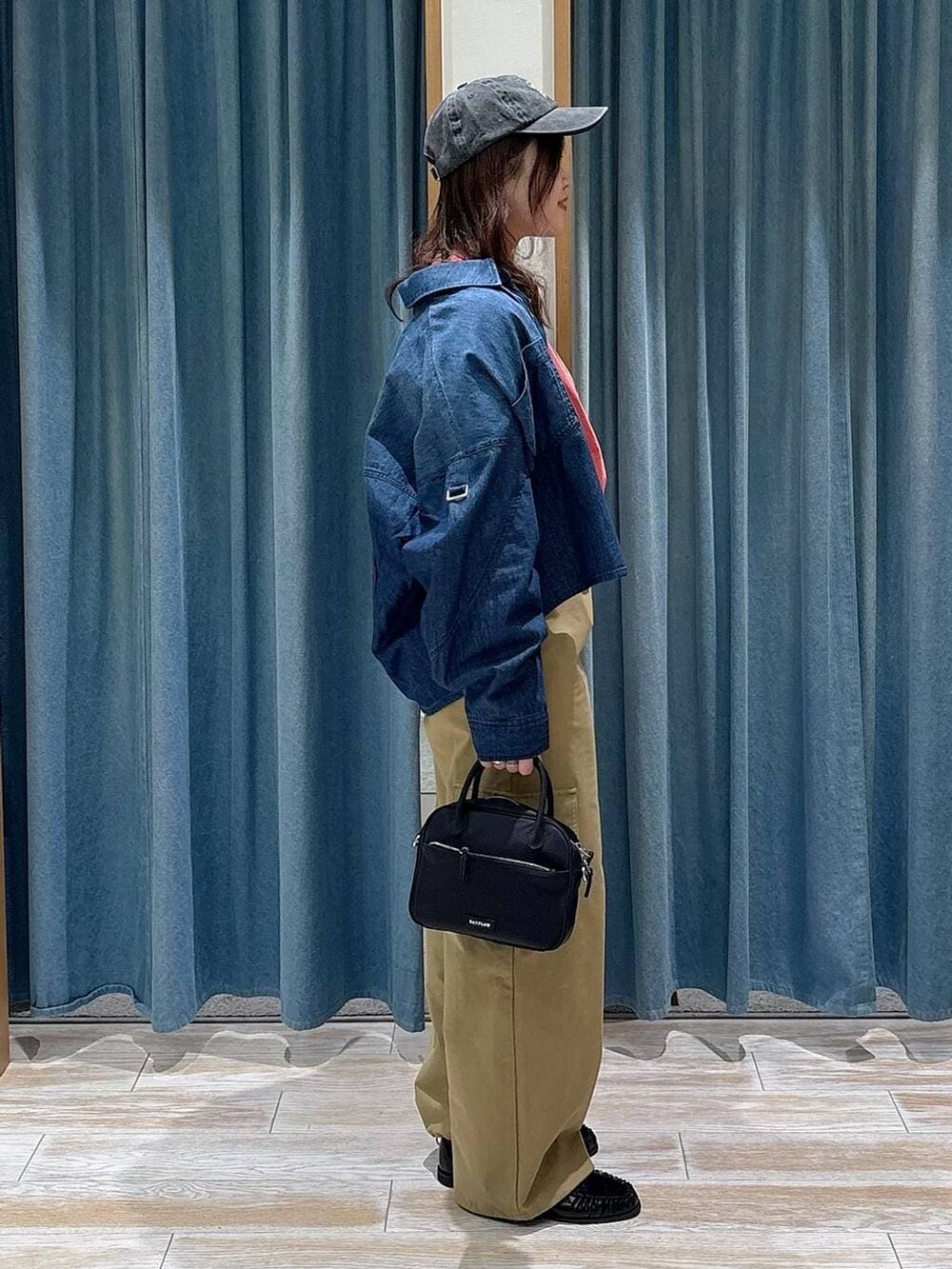 レッド系のTシャツ/カットソー、ブラック系のハンドバッグ、ブラック系のローファーを着用したレディースの冬コーディネートの3枚目の写真