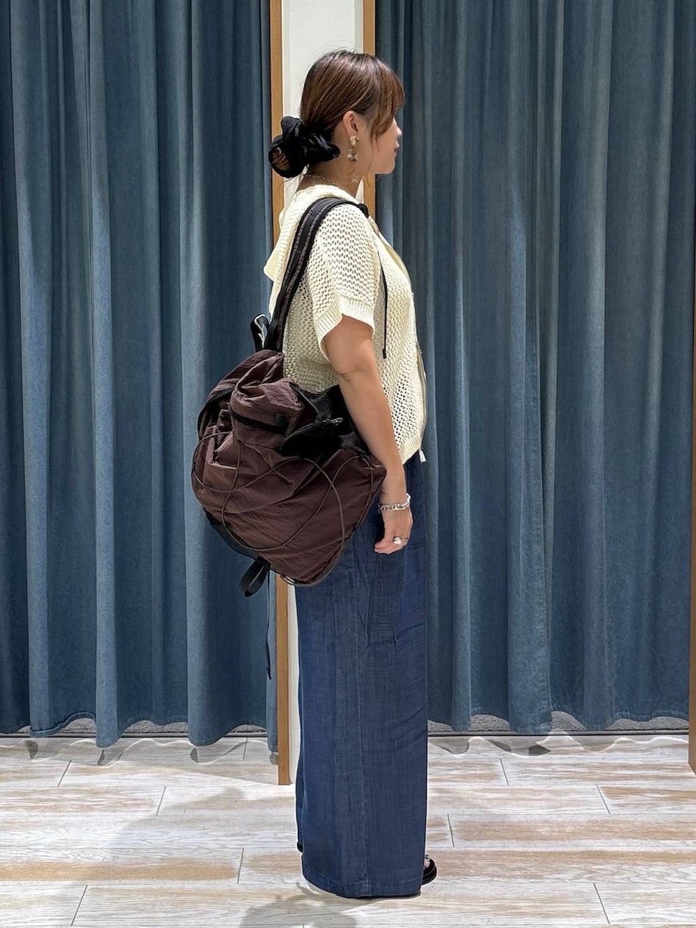 ブラウン系のバックパック/リュック、ブルー系のデニムパンツ、ブラック系のサンダルを着用したレディースの夏コーディネートの2枚目の写真