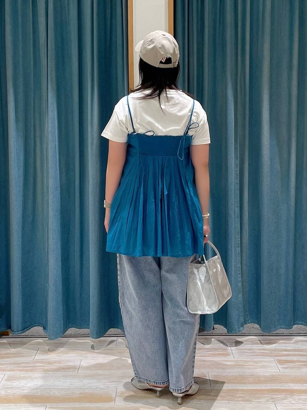 ブルー系のデニムパンツ、ホワイト系のTシャツ/カットソー、シルバー系のサンダルを着用したレディースの春コーディネートの3枚目の写真