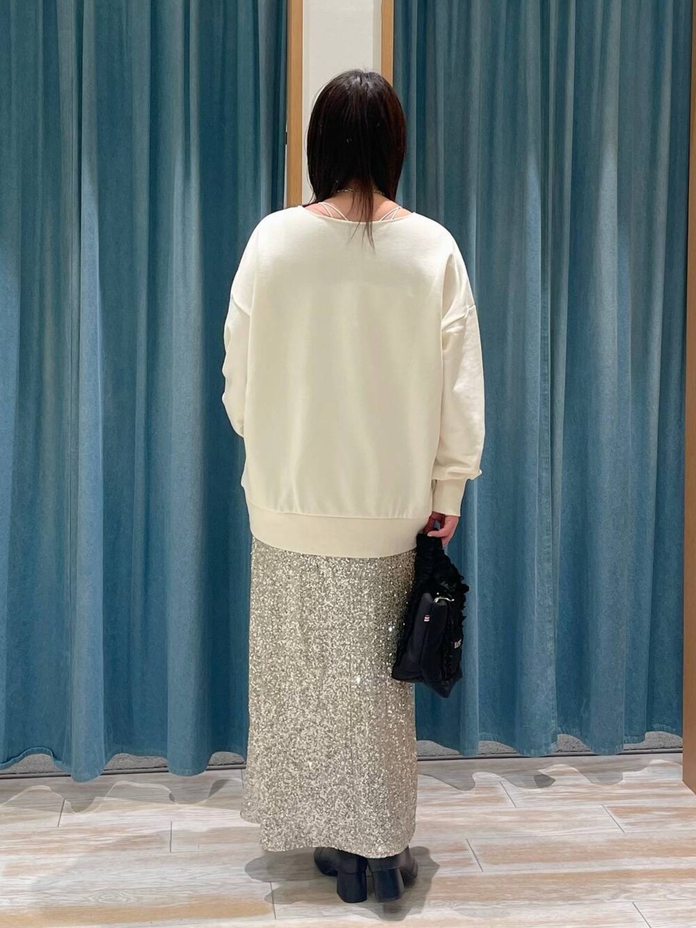 ブラック系のブーツ、ベージュ系のスカート、ブラック系のトートバッグを着用したレディースの冬コーディネートの3枚目の写真