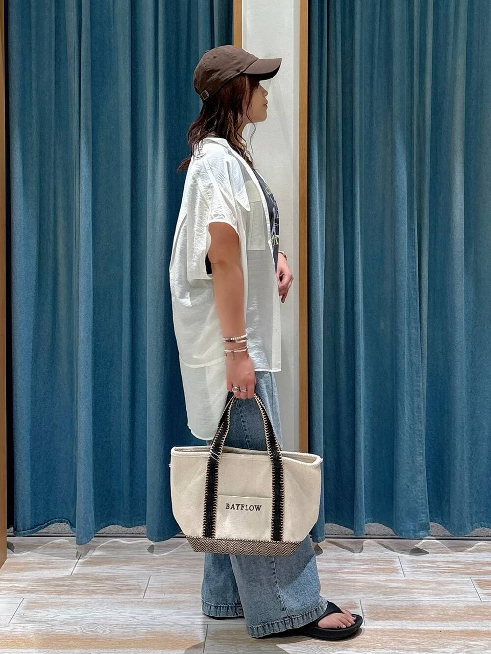 ホワイト系のシャツ/ブラウス、ベージュ系のトートバッグ、ブルー系のデニムパンツを着用したレディースの夏コーディネートの2枚目の写真