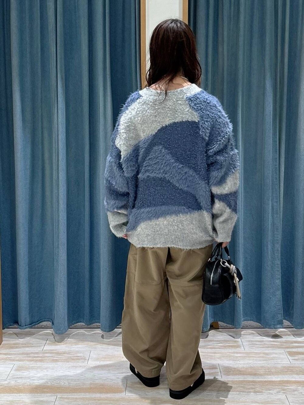 ブラック系のボストンバッグ、ブラック系のブーツ、ブルー系のカーディガン/ボレロを着用したレディースの秋コーディネートの3枚目の写真