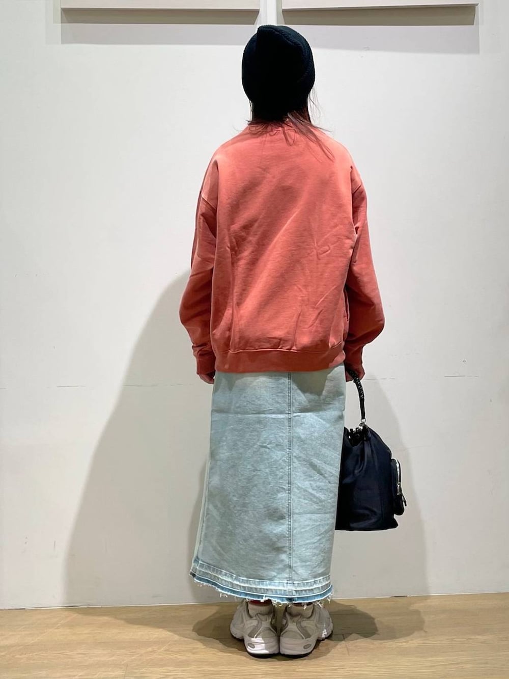 ブルー系のデニムスカート、ブラック系のショルダーバッグ、オレンジ系のTシャツ/カットソーを着用したレディースの秋コーディネートの2枚目の写真