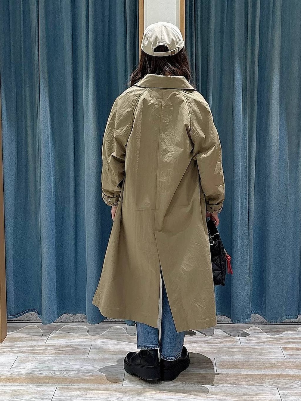 ブラック系のショルダーバッグ、ブラック系のブーツ、ブルー系のデニムパンツを着用したレディースの冬コーディネートの3枚目の写真