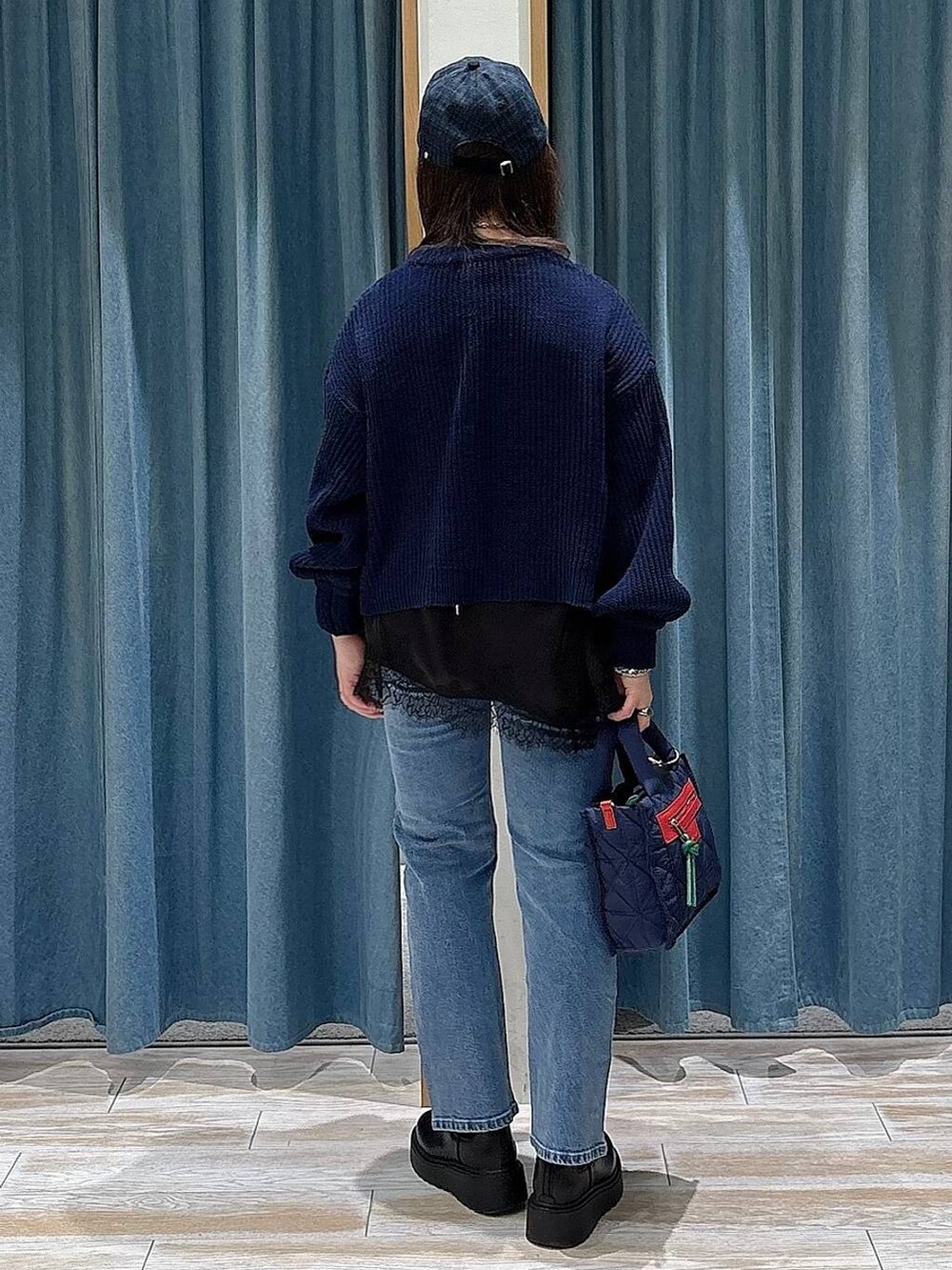 ブルー系のショルダーバッグ、ブラック系のブーツ、ブルー系のニット/セーターを着用したレディースの冬コーディネートの3枚目の写真