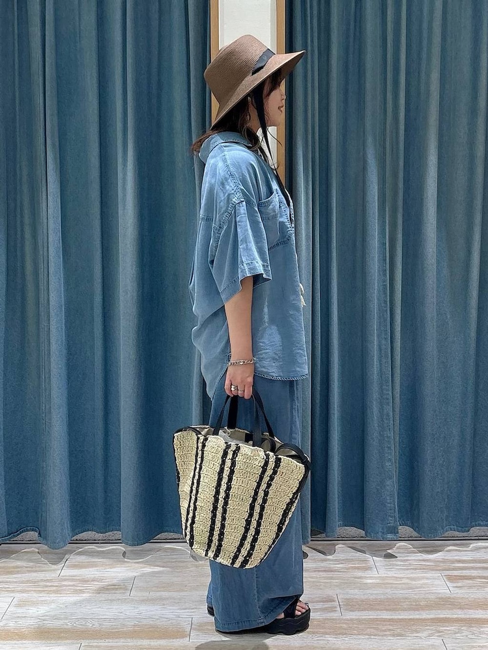 ブルー系のシャツ/ブラウス、ブルー系のデニムパンツ、ベージュ系のトートバッグを着用したレディースの春コーディネートの2枚目の写真