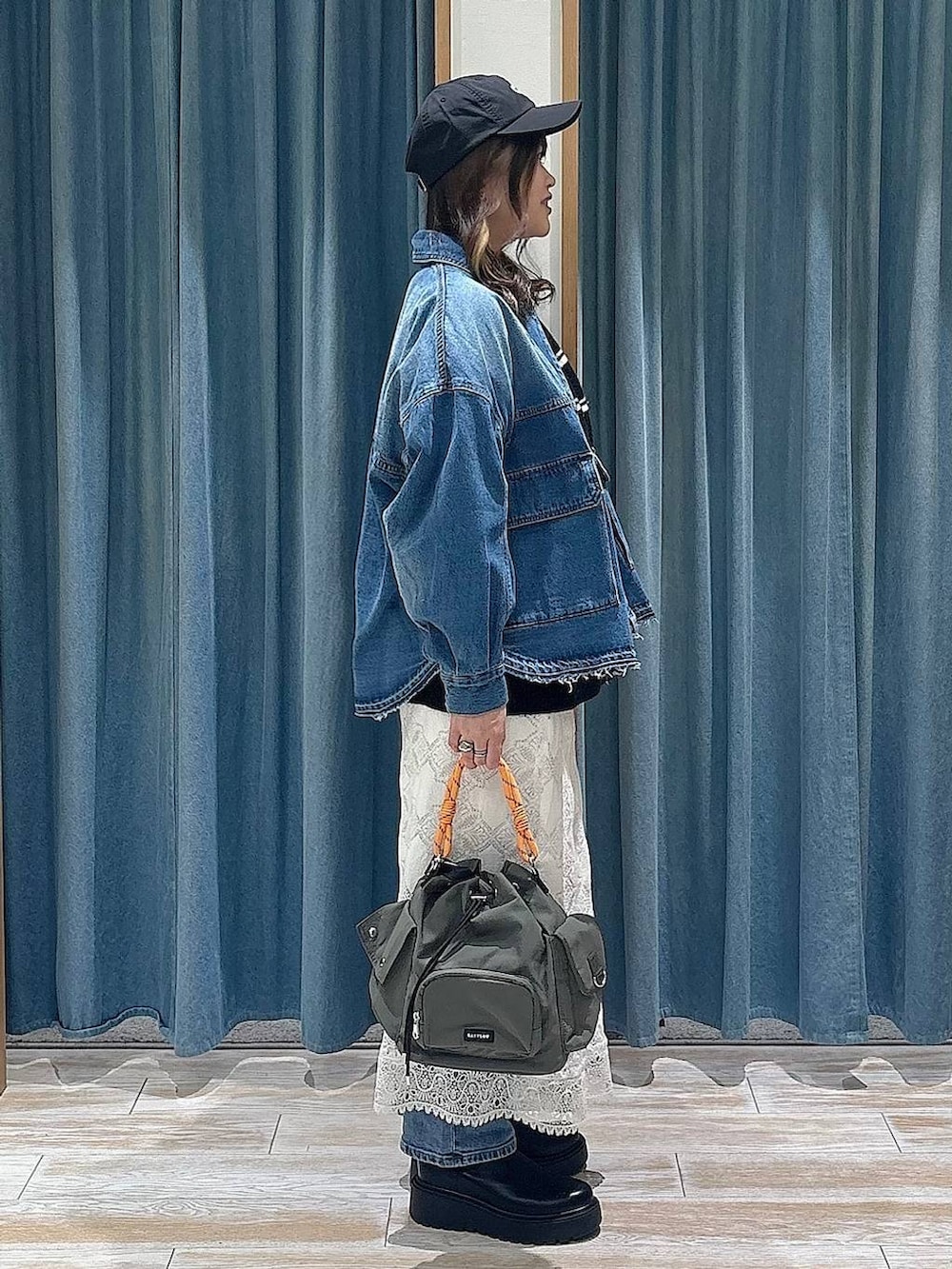 ブラック系のブーツ、グリーン系のハンドバッグ、ブラック系のニット/セーターを着用したレディースの冬コーディネートの2枚目の写真