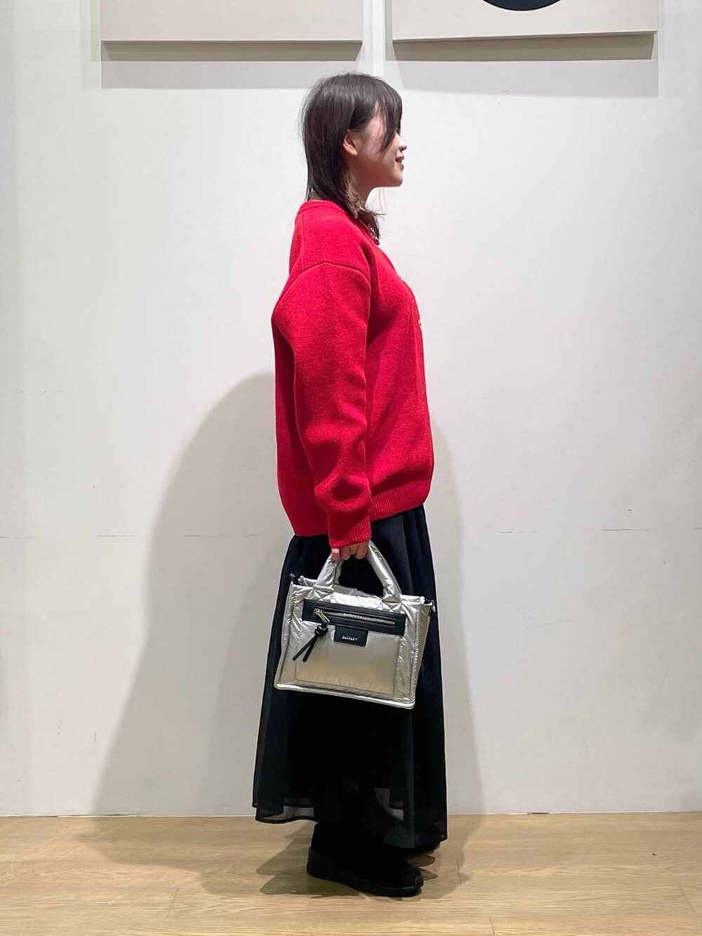 シルバー系のショルダーバッグ、ブラック系のブーツ、レッド系のニット/セーターを着用したレディースの秋コーディネートの2枚目の写真