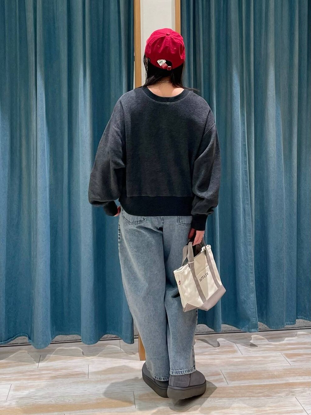 グレー系のブーツ、グレー系のトートバッグ、ブルー系のデニムパンツを着用したレディースの冬コーディネートの3枚目の写真