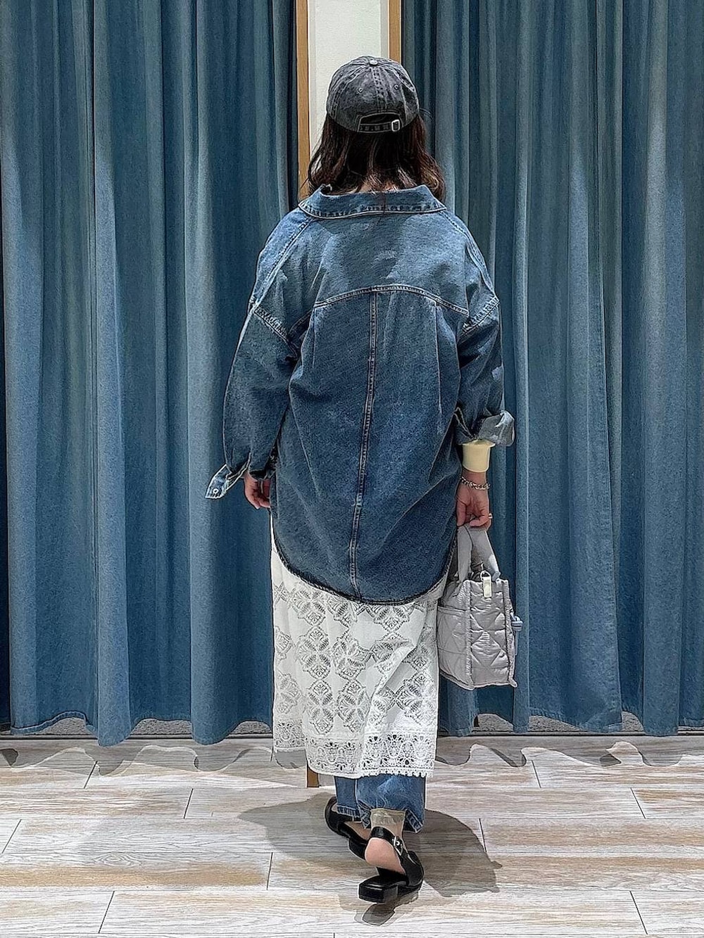 グレー系のショルダーバッグ、ブラック系のパンプス、ブルー系のデニムパンツを着用したレディースの冬コーディネートの3枚目の写真