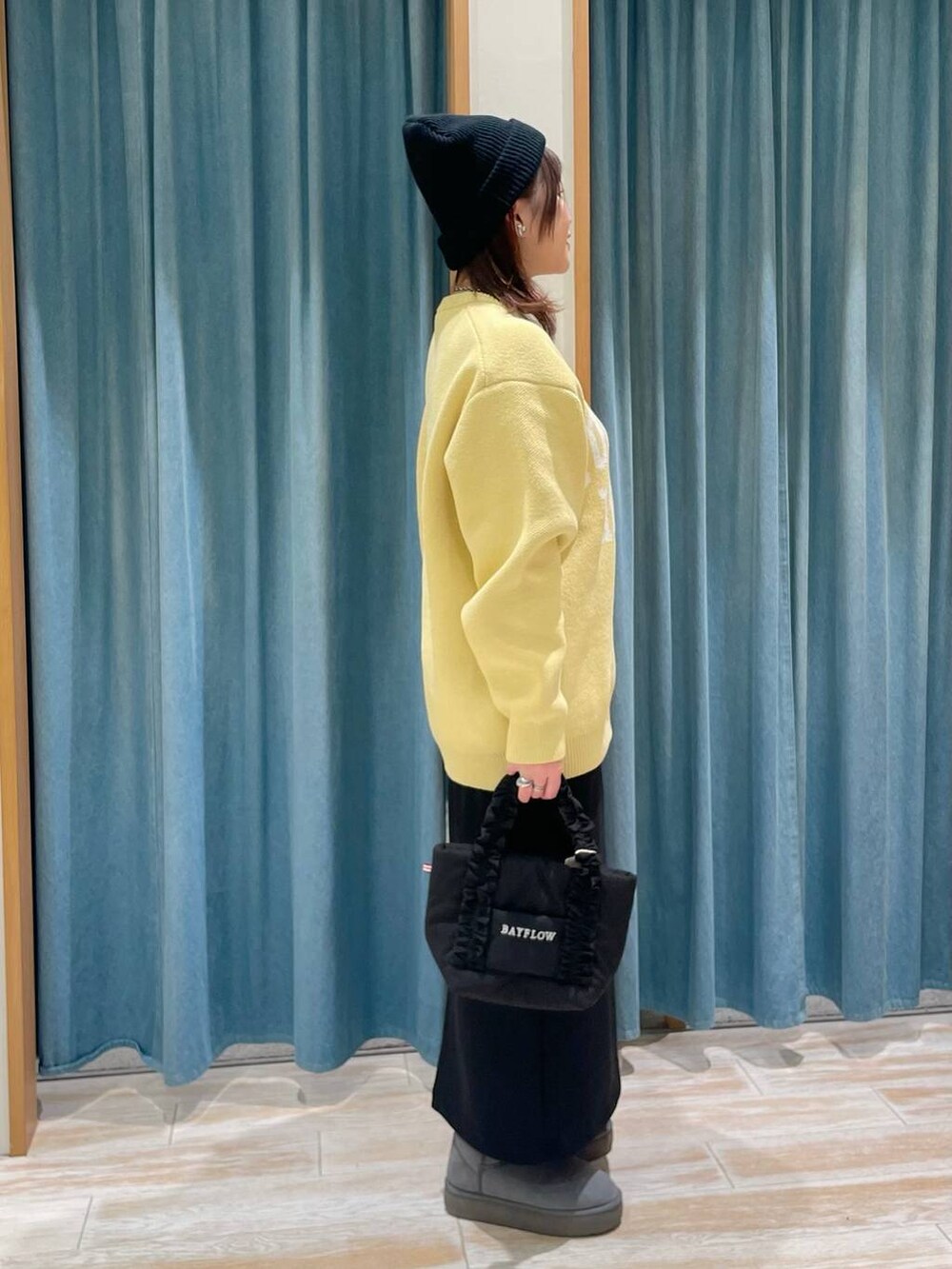 イエロー系のニット/セーター、グレー系のブーツ、ブラック系のトートバッグを着用したレディースの冬コーディネートの2枚目の写真