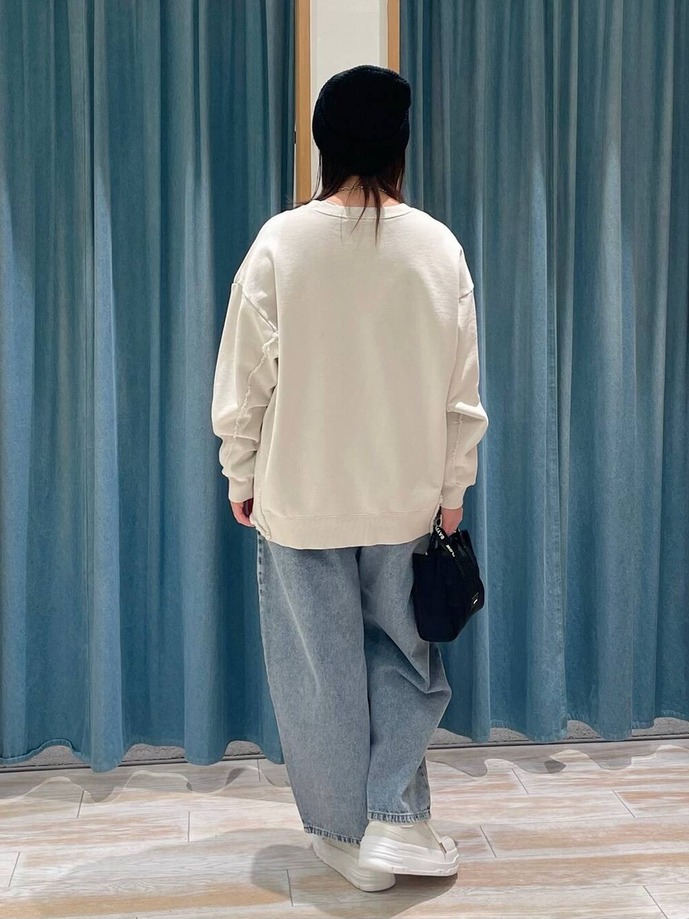 ホワイト系のスニーカー、ブルー系のデニムパンツ、ブラック系のショルダーバッグを着用したレディースの冬コーディネートの3枚目の写真