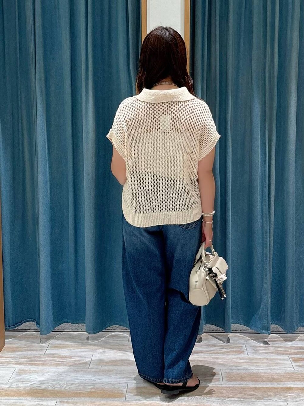 ブルー系のデニムパンツ、ブラック系のサンダル、ホワイト系のボストンバッグを着用したレディースの夏コーディネートの3枚目の写真