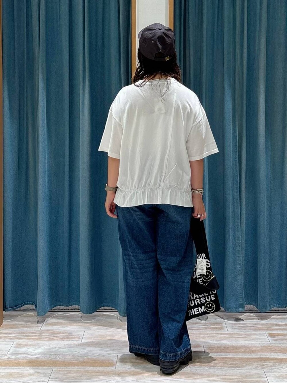 ブルー系のデニムパンツ、ブラック系のトートバッグ、シルバー系のネックレスを着用したレディースの夏コーディネートの3枚目の写真