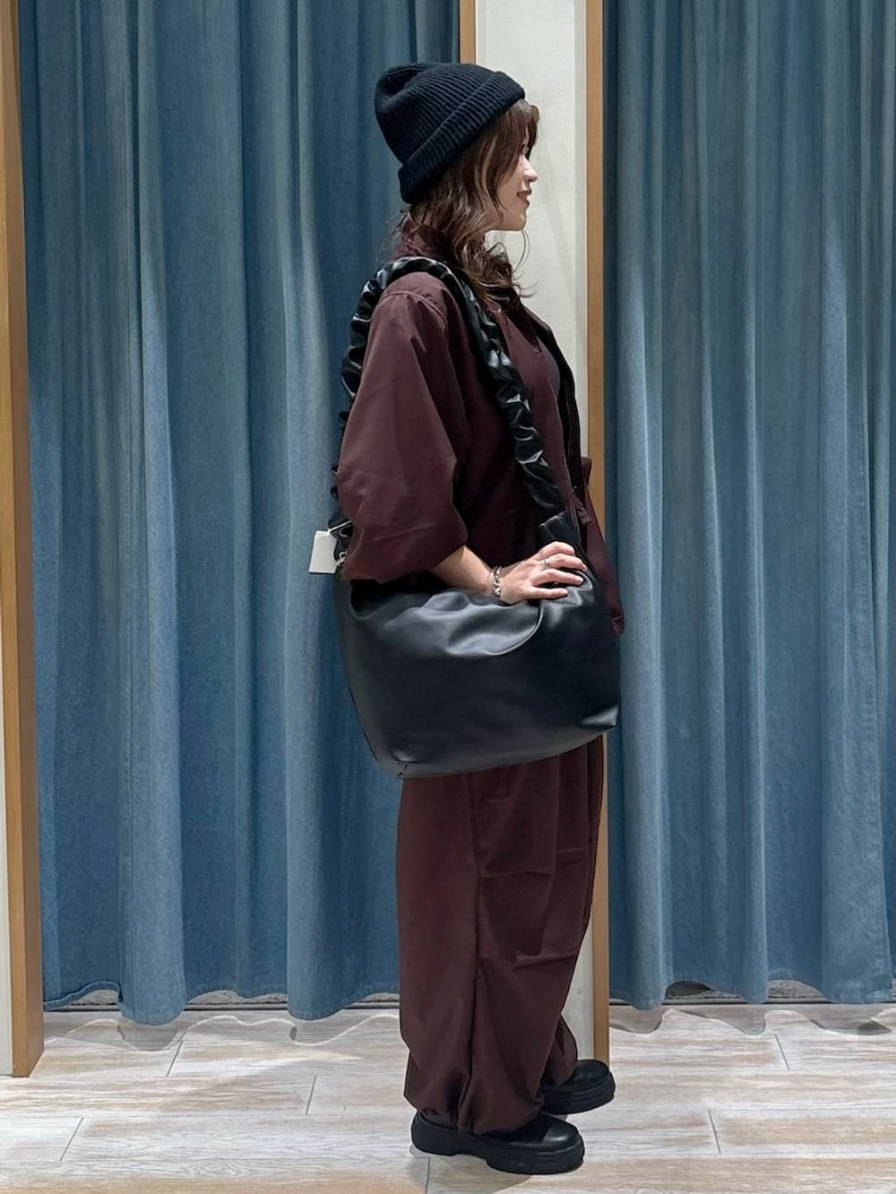 ブラック系のブーツ、ブラック系のショルダーバッグ、グレー系のネックレスを着用したレディースの秋コーディネートの2枚目の写真