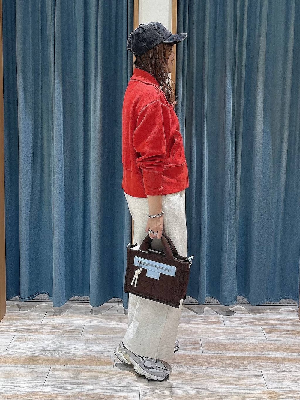 ブラウン系のショルダーバッグ、レッド系のスウェット、ホワイト系のスウェットパンツを着用したレディースの秋コーディネートの2枚目の写真
